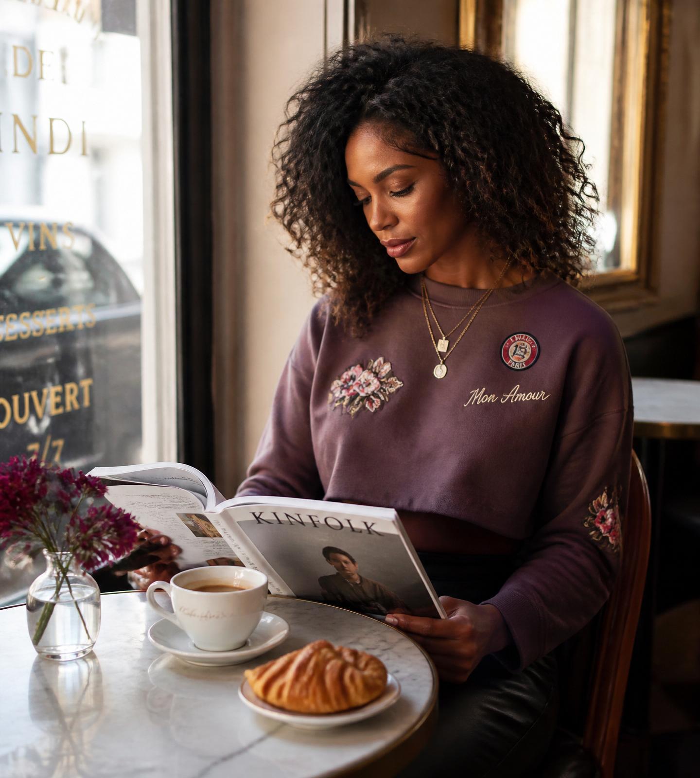Woman in a patched crop sweatshirt at a café